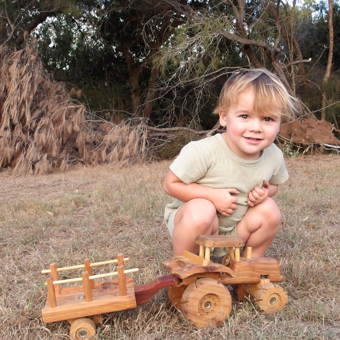 Toddler Boy playing with Handmade Wooden Tracor Trailer Toy. Removable Trailer. Suspension. Rolling Wheels. Push pull. Durable Quality. In Australian Bush. Australian Made