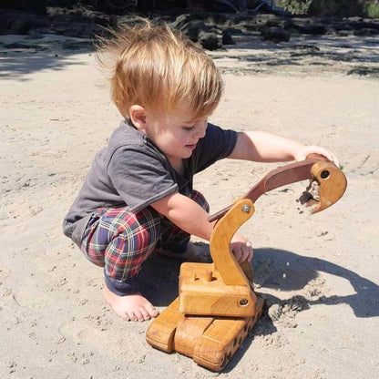 Big Large luxury Handmade Wooden Toy Excavator Digger. Heirloom. Durable. Functional Arm, boom, blade. Rotating Cab. pre-school boy playing with digger, digging sand on beach.