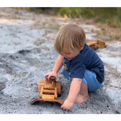 A toddler boy happily engaging in imaginative and role playing with his handcrafted wooden Bulldozer. Utilising the moving blade.