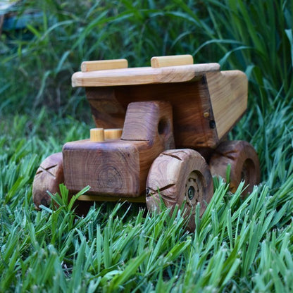 A Big Chunky Quality Handmade wooden dump truck, showcasing large functional tip tray and realistic cab. Huge tyres. Cartoon like design.