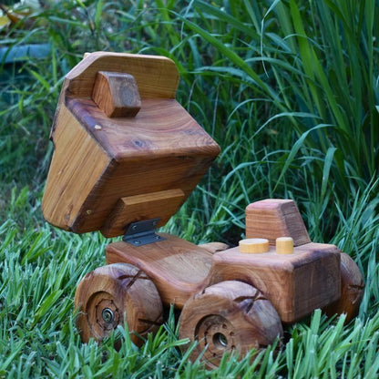 Durable Handmade wooden dump truck toy showcasing functional and extended dump body or tip tray. Curved body and cartoon style cab and smoke stacks. Beautiful wood grain showing quality materials and woodworking craftmanship.