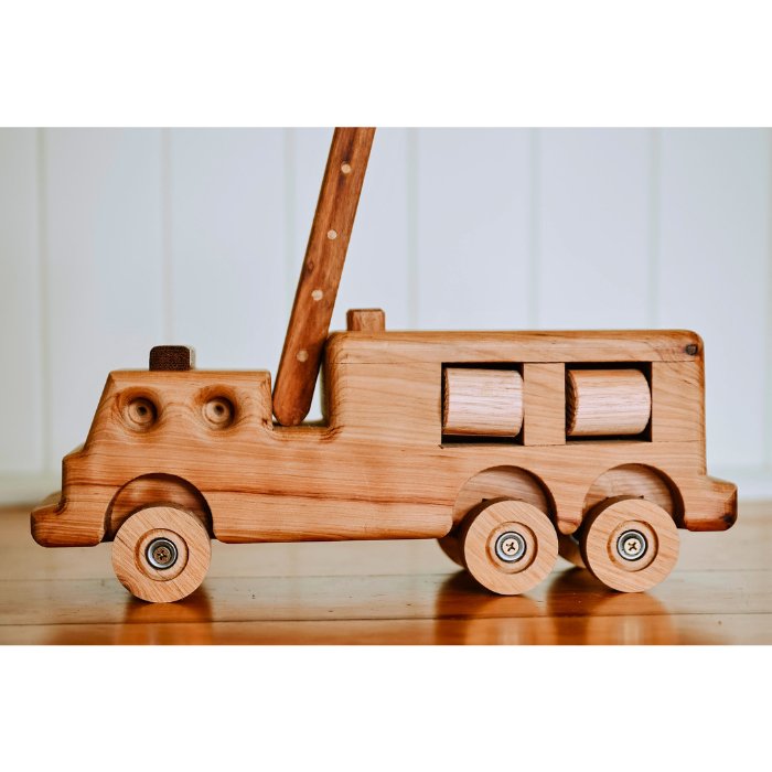 Premium Heirloom quality Australian handmade wooden fire truck toy. Showcasing detail and features such as suspension working ladder and rolling hose reels. In luxury queenslander home.