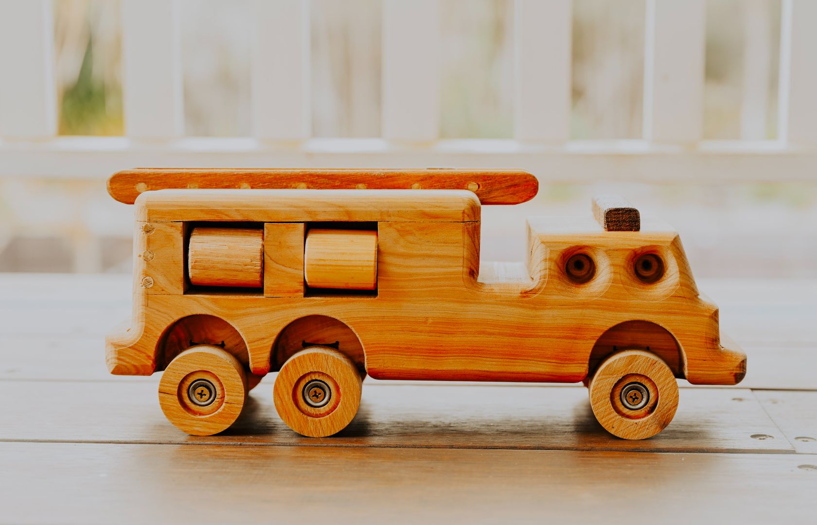 Side view of premium quality heirloom wooden fire truck. Showing premium and luxury features and design of rolling hose reels ladder moving wheels and suspension. Sustainable materials