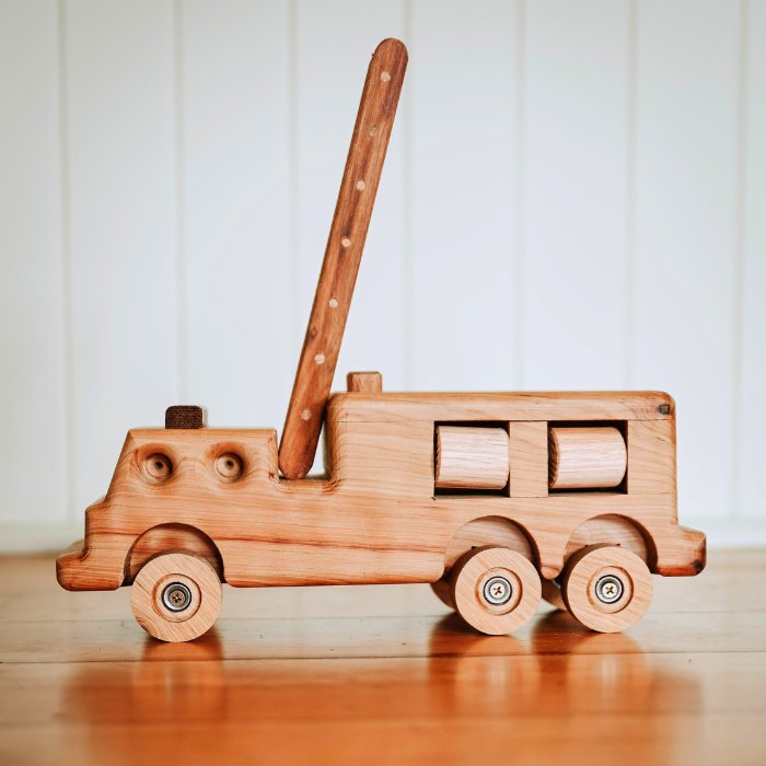 Premium quality wooden fire truck toy with ladder extended. Showcasing rolling hose reels and suspension. In luxury Queenslander home.  