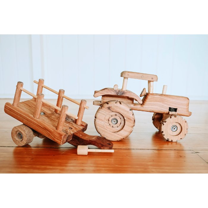 Handmade Wooden Tractor Trailer Toy. Showcasing features such as suspension big wheels and Removable Trailer. Suspension. Rolling Wheels. Push pull. Durable Quality. Professional photo in Queenslander on wooden floorboards. 